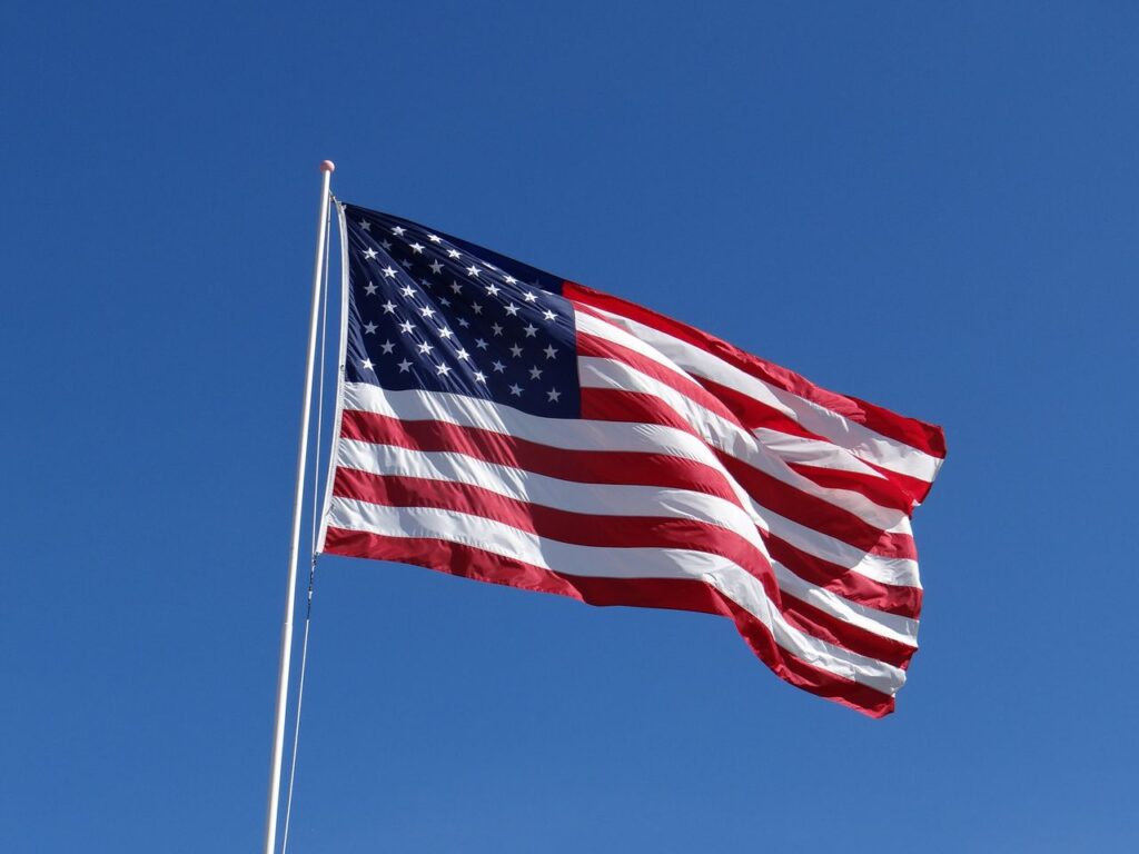 A vibrant American flag waves majestically against a clear blue sky in Mackinaw City, Michigan.
